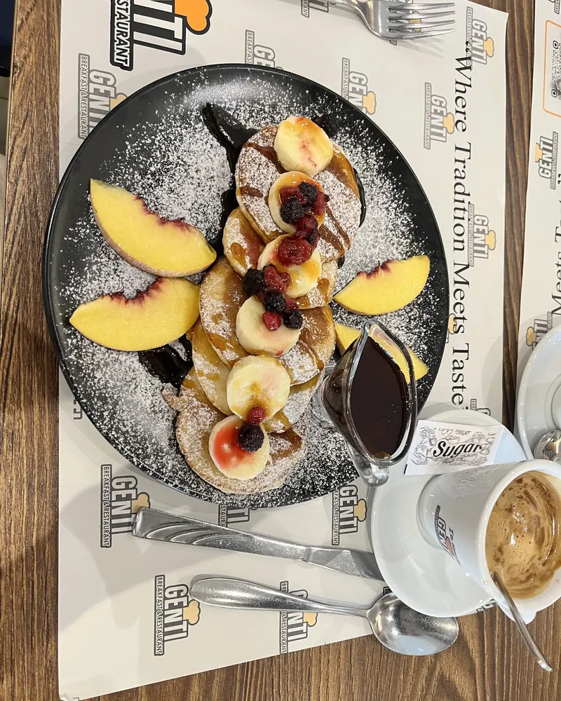 Pancakes with sliced peaches, berries and chocolate sauce