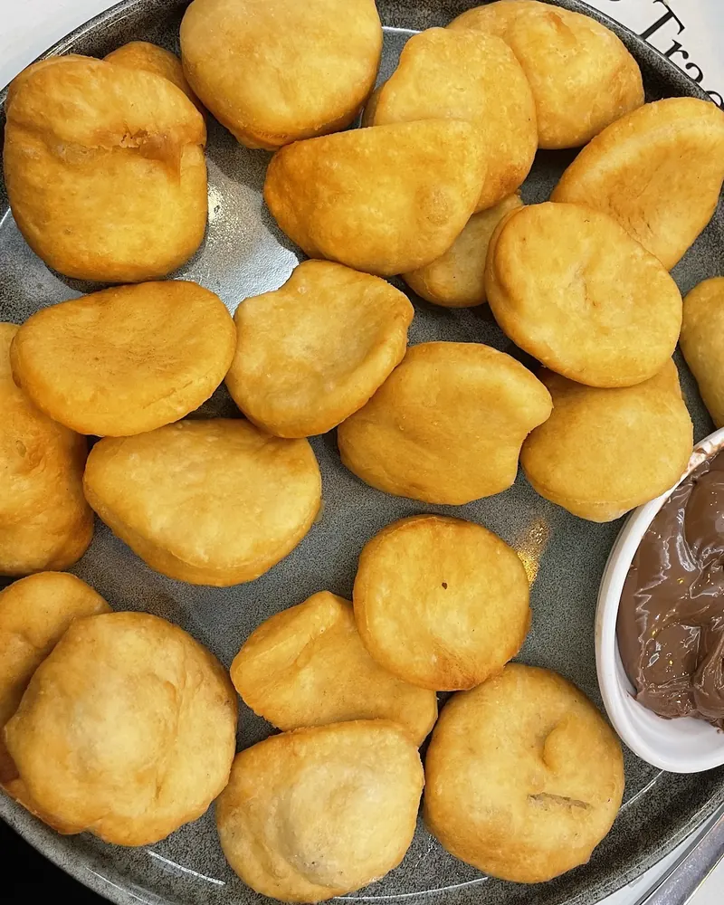 A plate of golden petulla with a bowl of Nutella on a Genti placemat